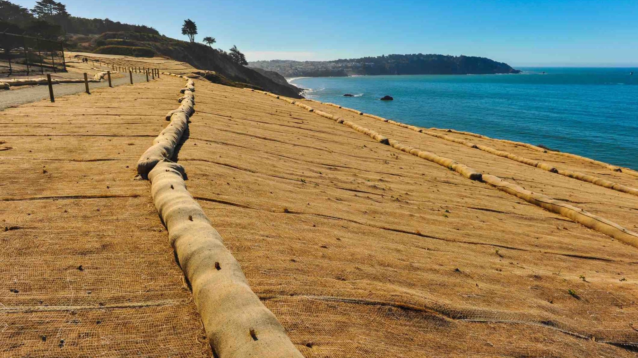 Waterside erosion control mesh and sand booms along a coast