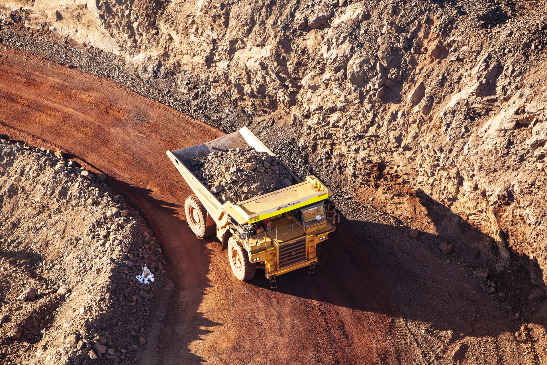 Aerial view of a loaded haul truck on a red-dirt mine haul road